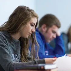 Students reviewing papers in a classroom.